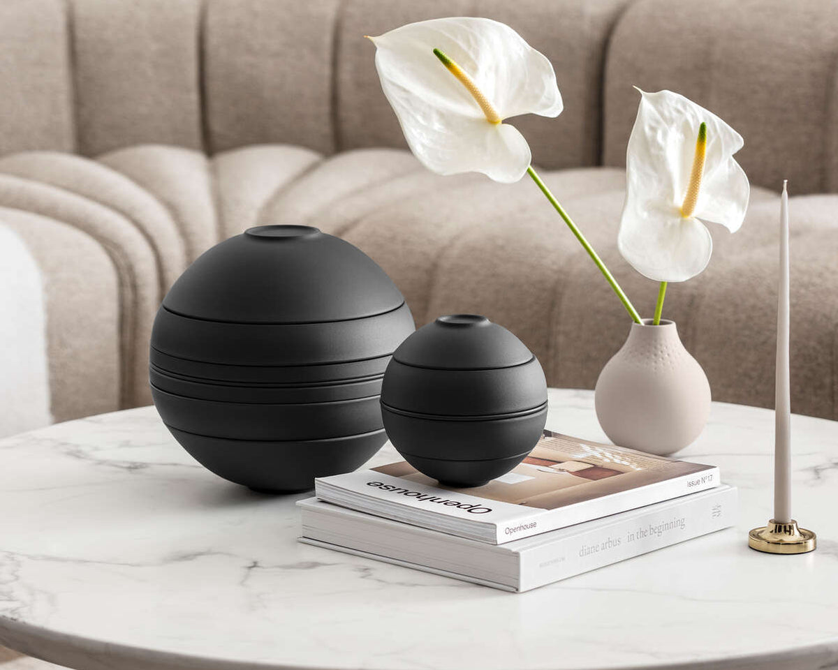 Decorative items on a coffee table including black spherical vases and a white flower arrangement.
