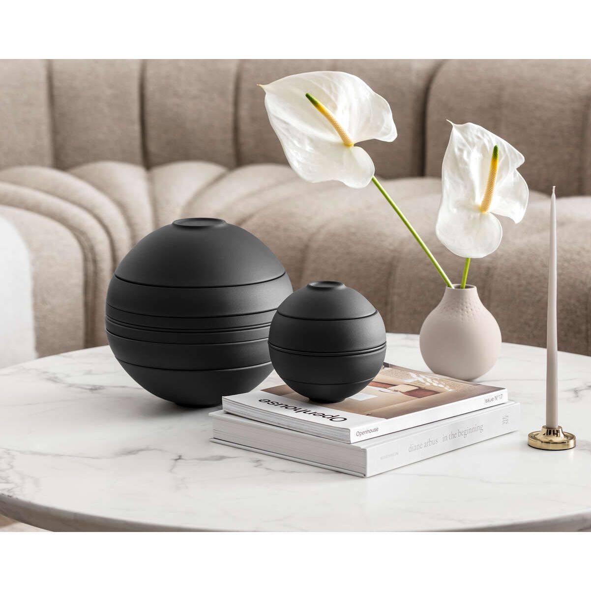Decorative items on a coffee table including black spherical vases and a white flower arrangement.