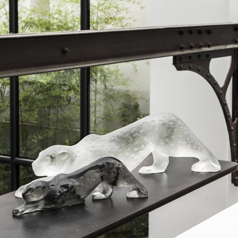 Two glass animal sculptures on a black surface with a blurred outdoor background