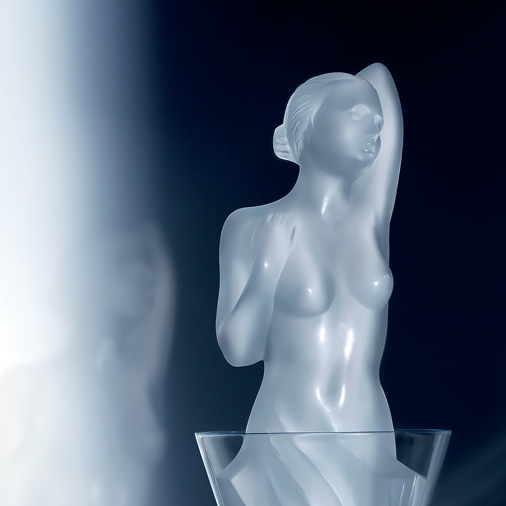 Glass sculpture of a nude woman on a dark background
