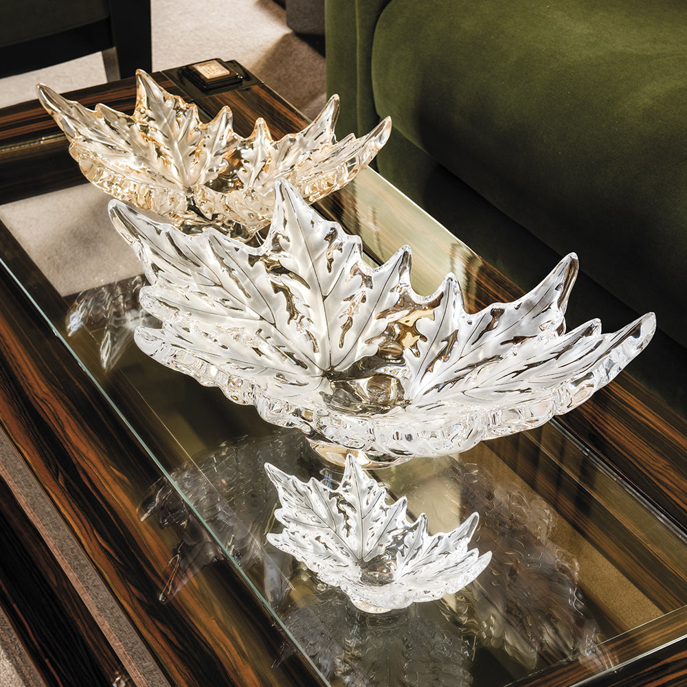 Decorative leaf-shaped crystal bowl on a reflective surface
