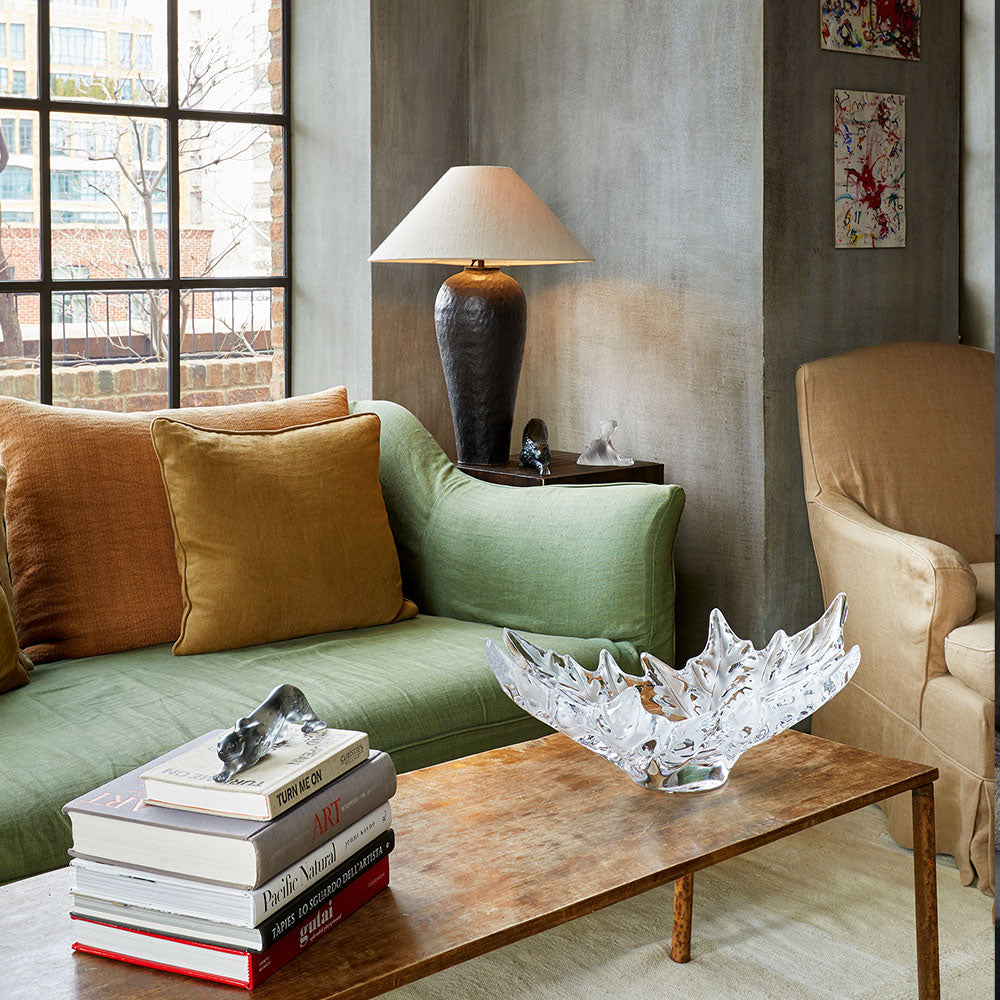 Living room with green sofa, books, lamp, and decorative bowl on a wooden table.