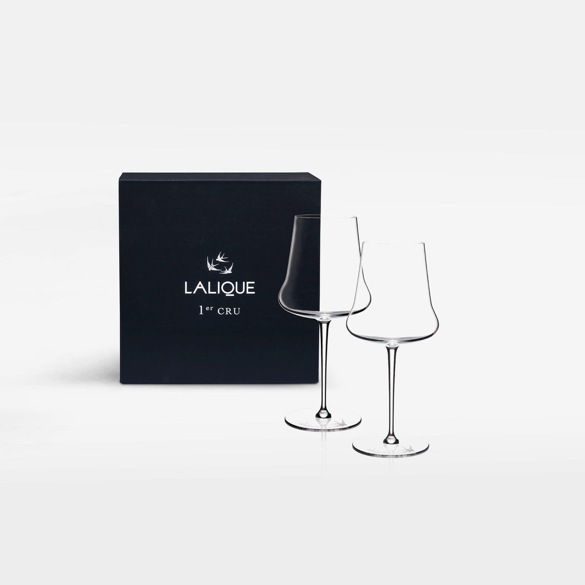 Two Lalique crystal wine glasses in front of a black box with the Lalique logo on a white background.