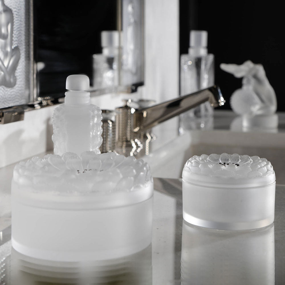 Frosted glass containers on a reflective surface with blurred background