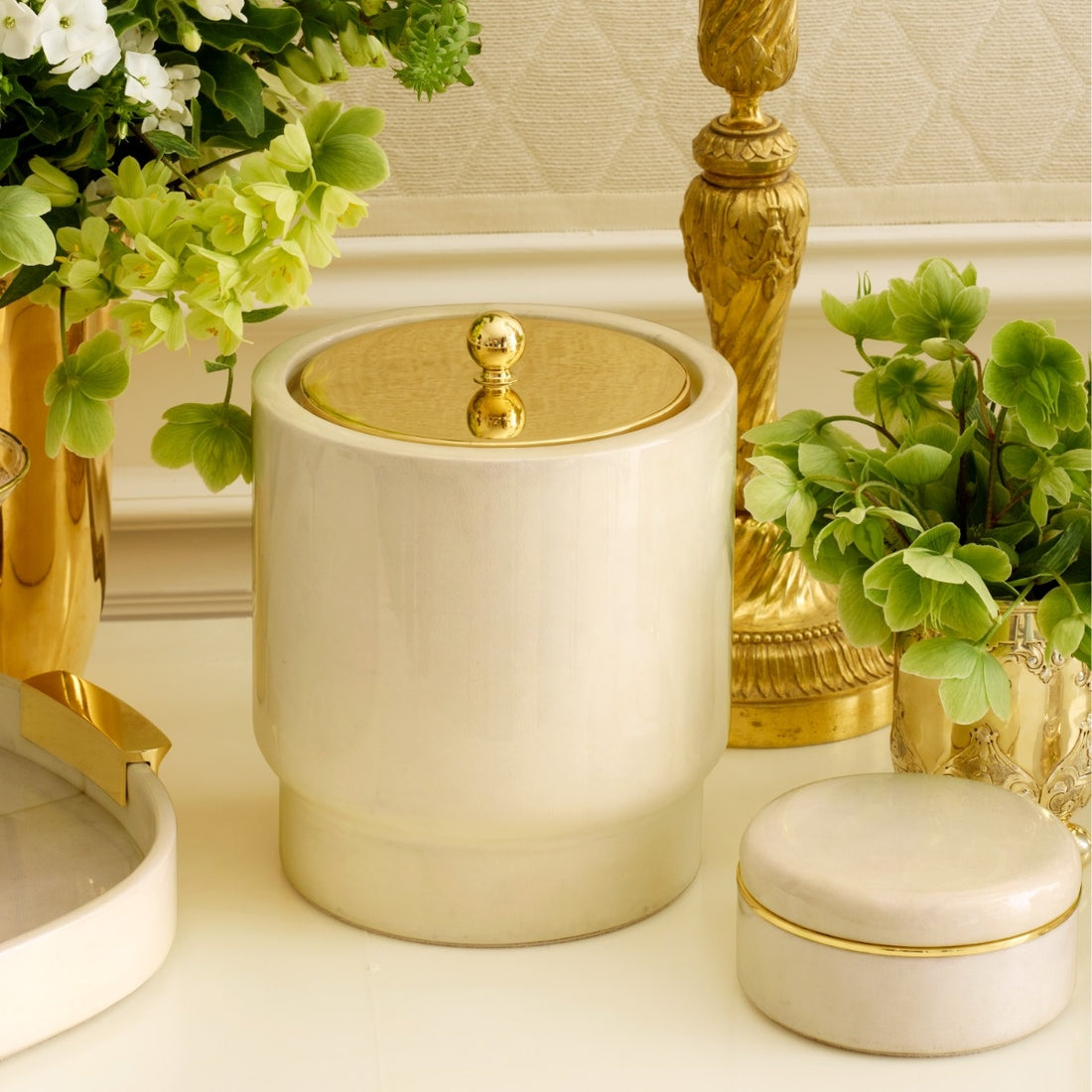 Cream-colored ceramic jar with a gold lid on a white background