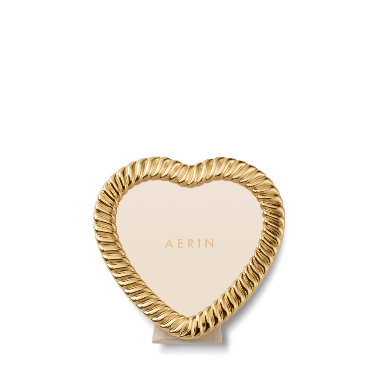 A heart-shaped picture frame with a twisted rope border and a light beige center, standing on a small matching base. The brand name 'AERIN' is printed in gold in the center.