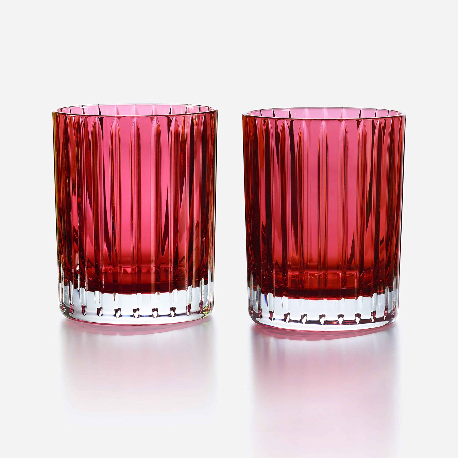 Two red glass tumblers with a textured design on a white background