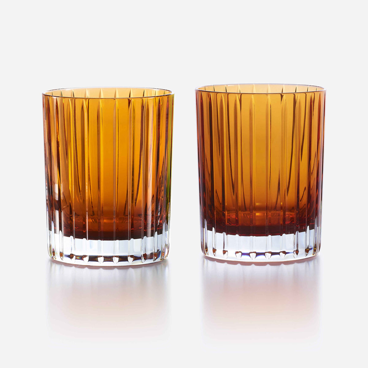 Two amber-colored glass tumblers on a white background