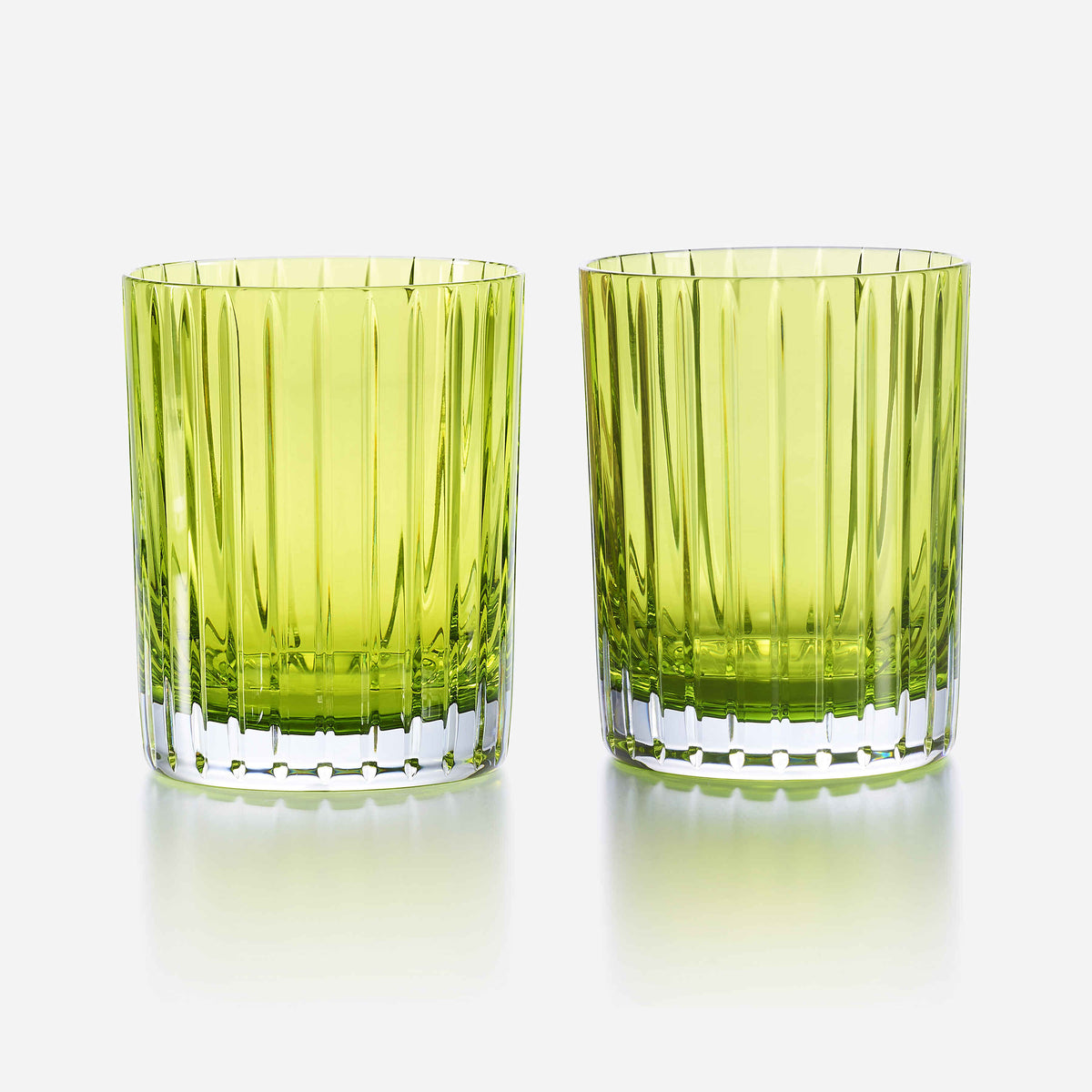 Two green glass tumblers with textured design on a white background