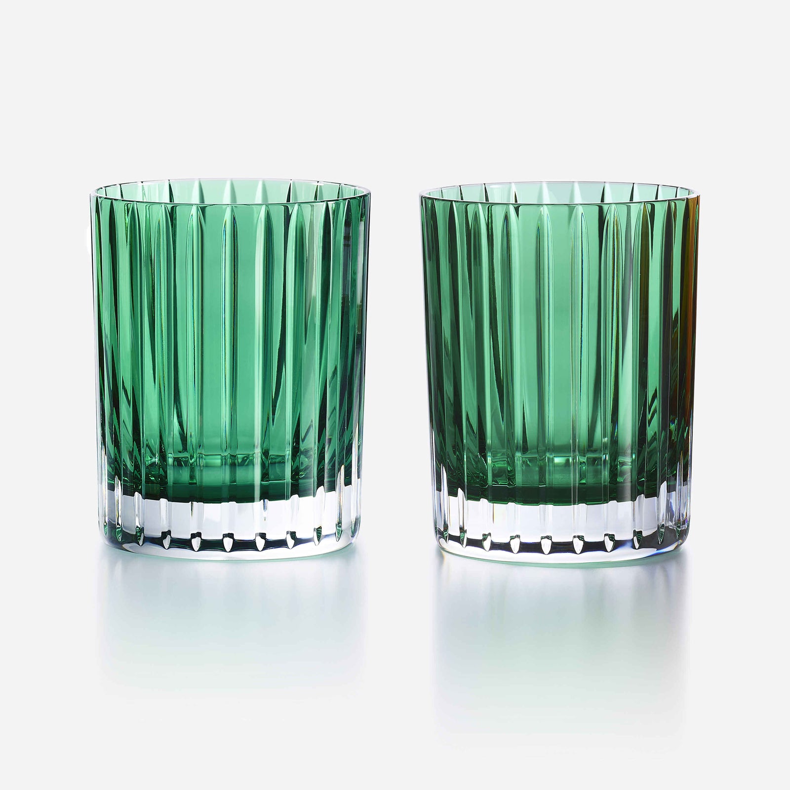 Two green glass tumblers with a textured design on a white background