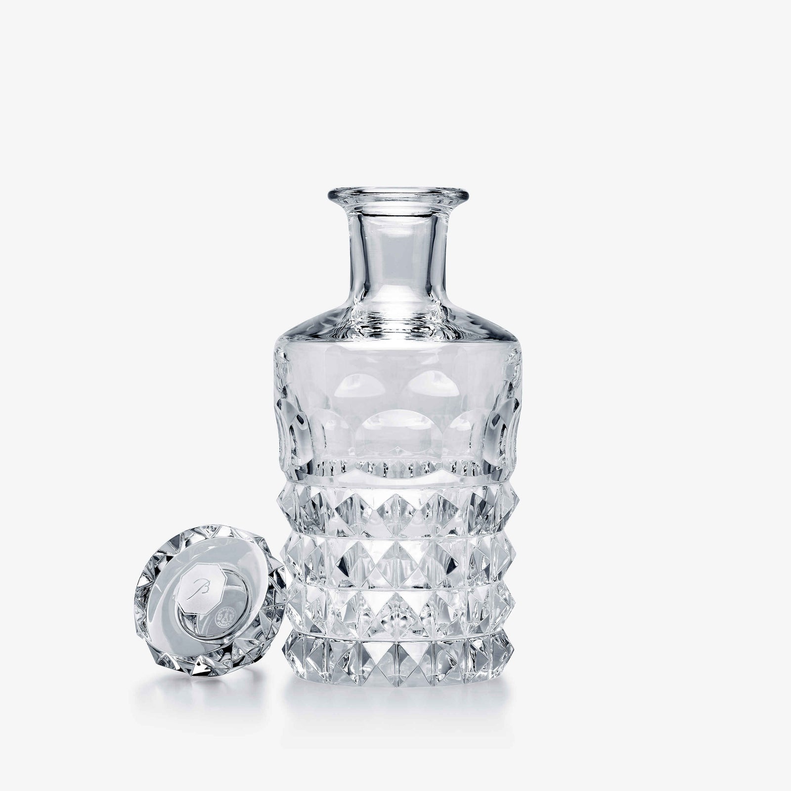 Clear glass decanter with diamond-cut design on a white background