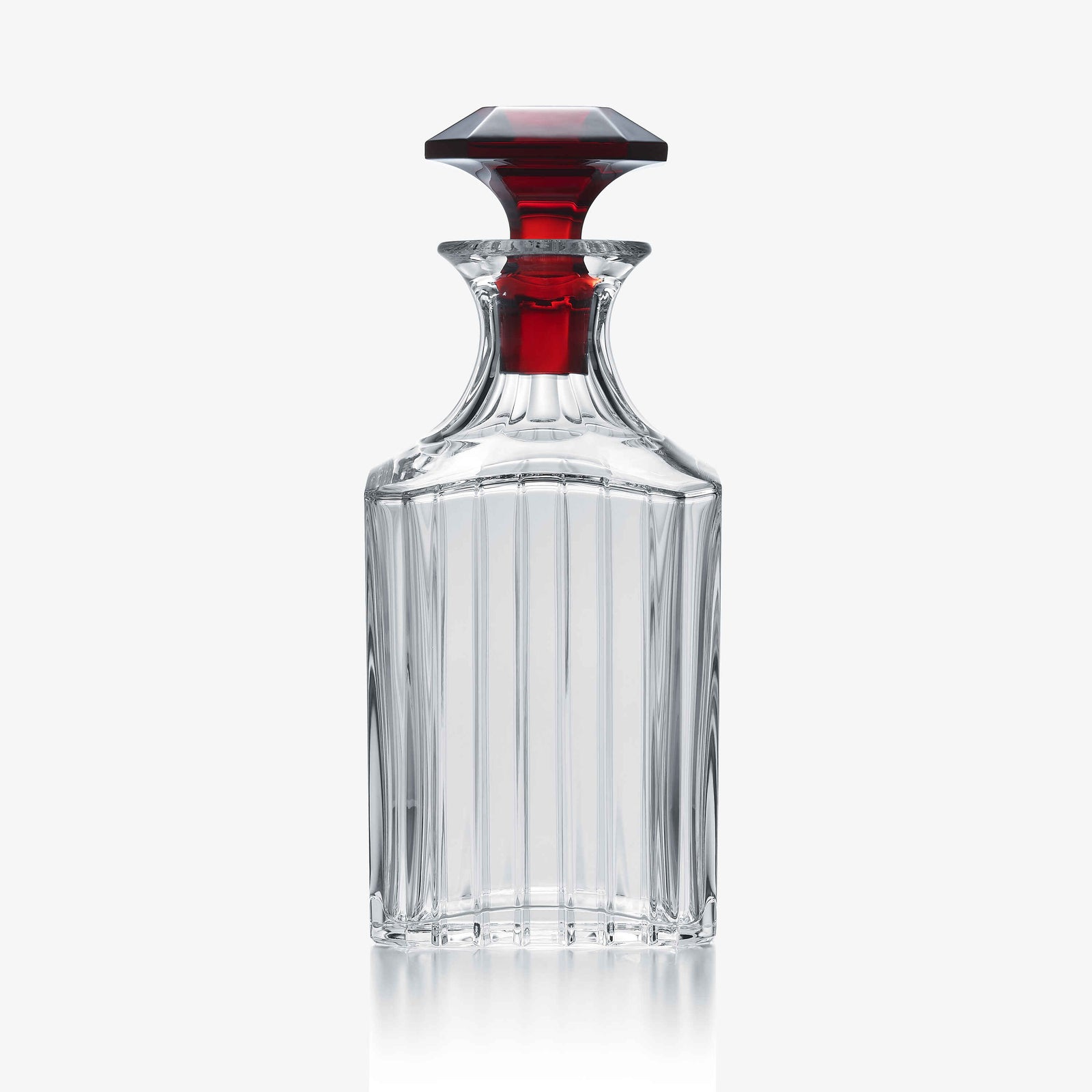 Clear crystal decanter with a red stopper on a white background