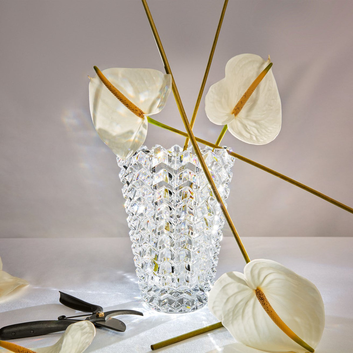 Clear crystal vase with decorative flowers on a light surface
