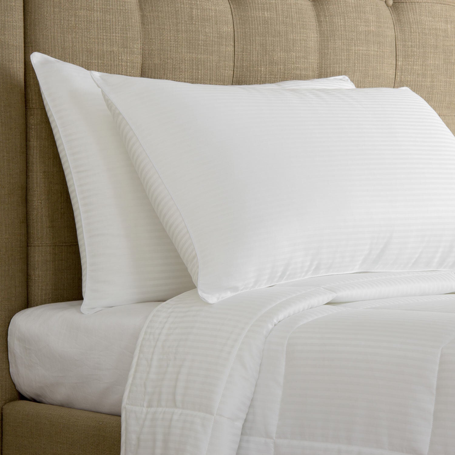 Two white pillows on a bed with a beige headboard
