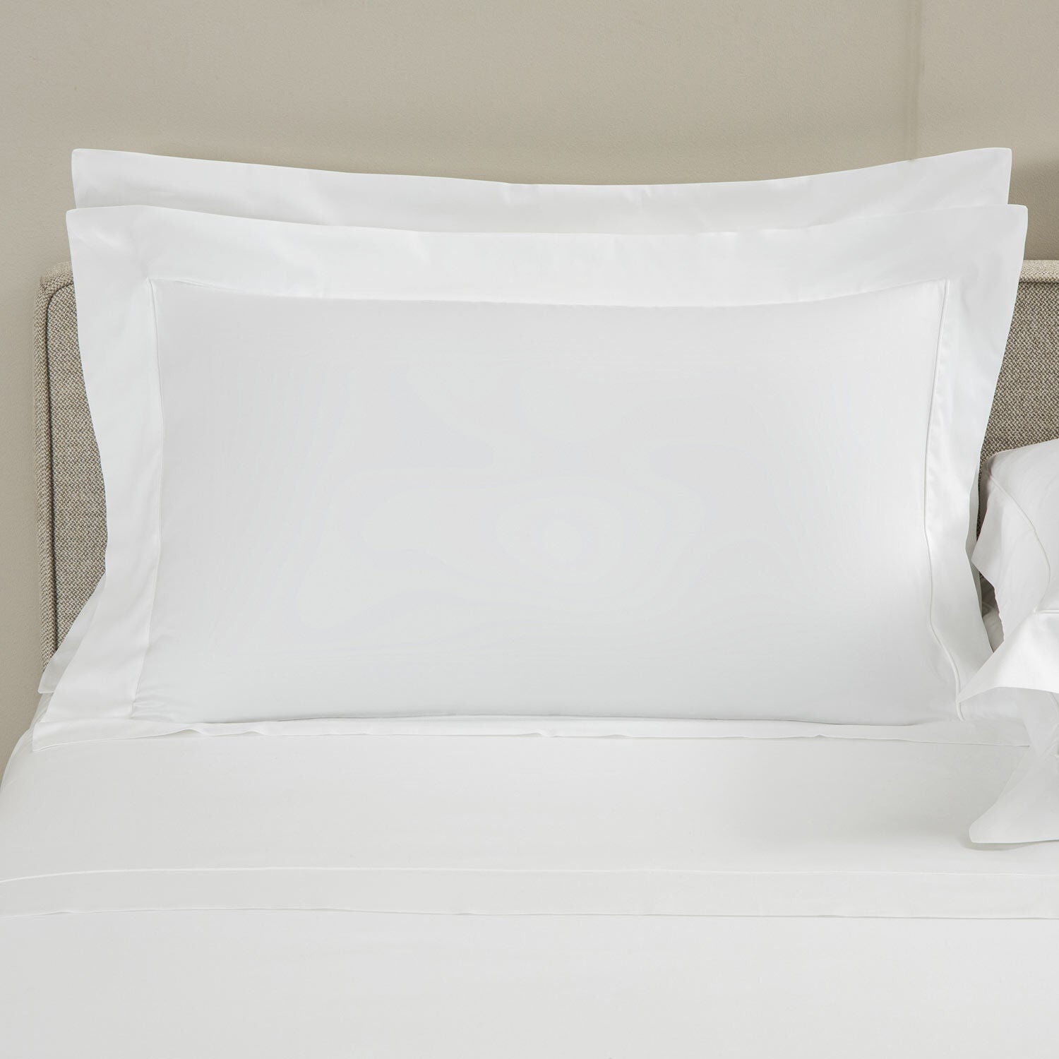 White pillows on a bed with a neutral headboard
