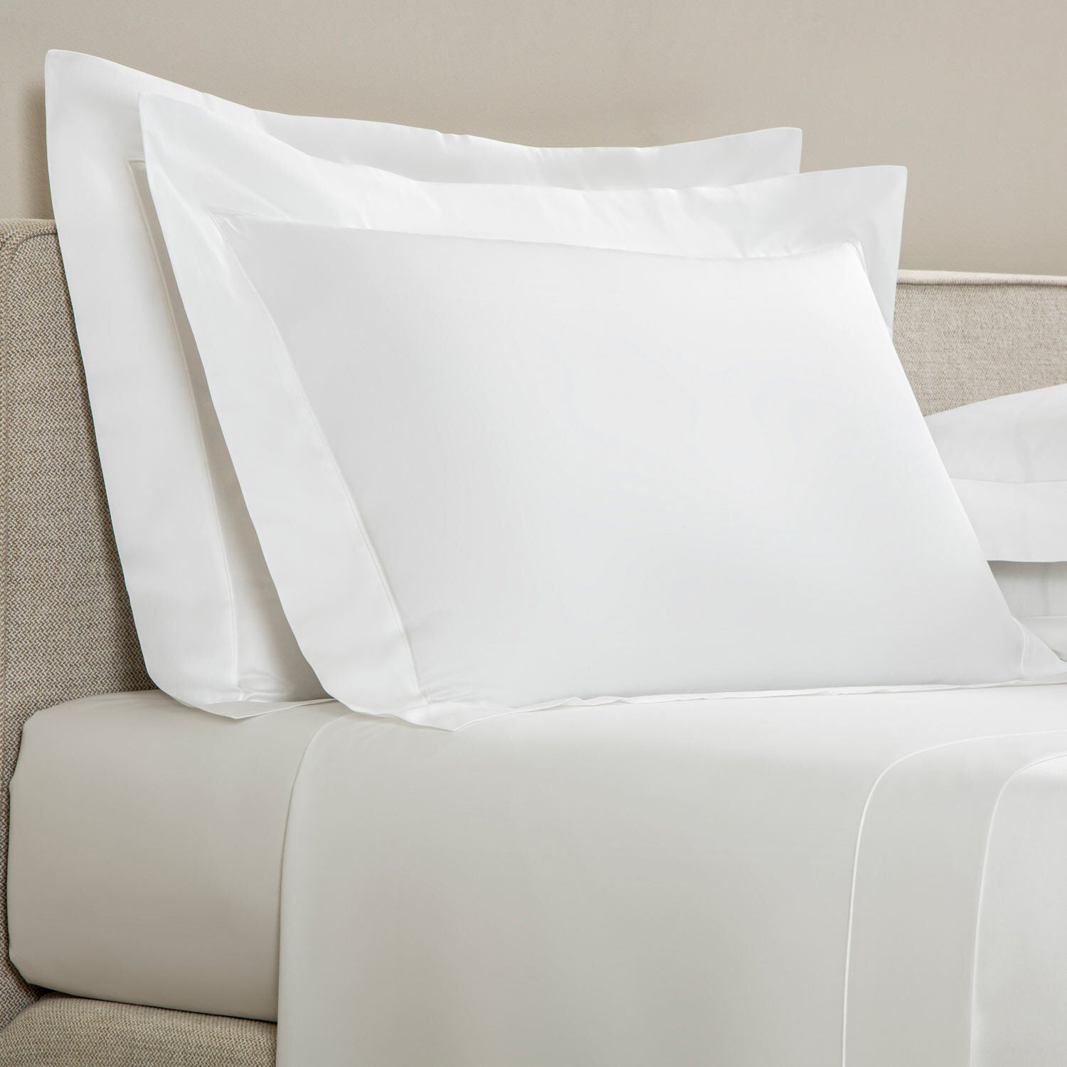 White pillows on a bed with a neutral headboard