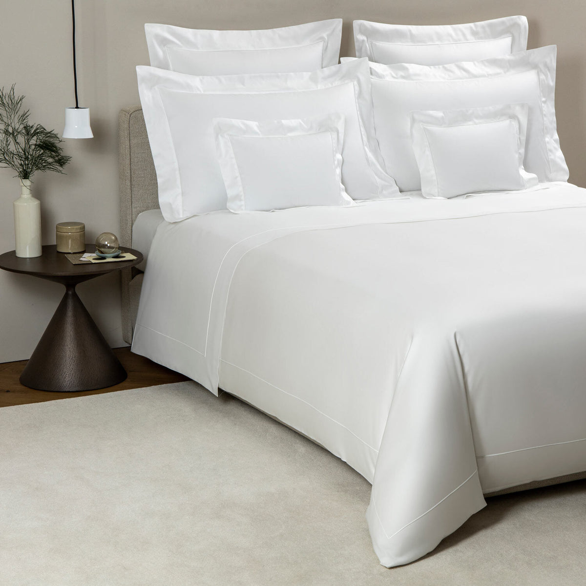 White bedding set on a bed with a side table in the background