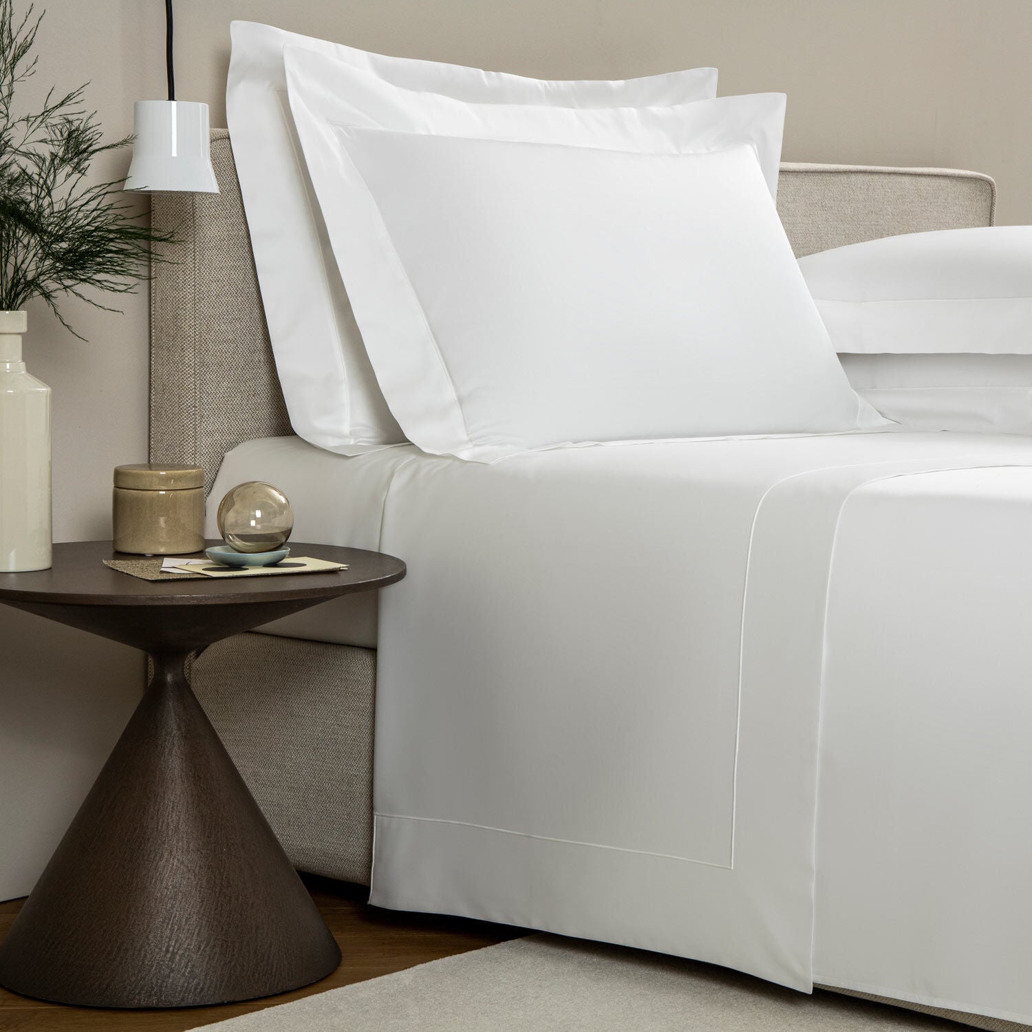 Neatly made bed with white bedding in a bedroom setting.