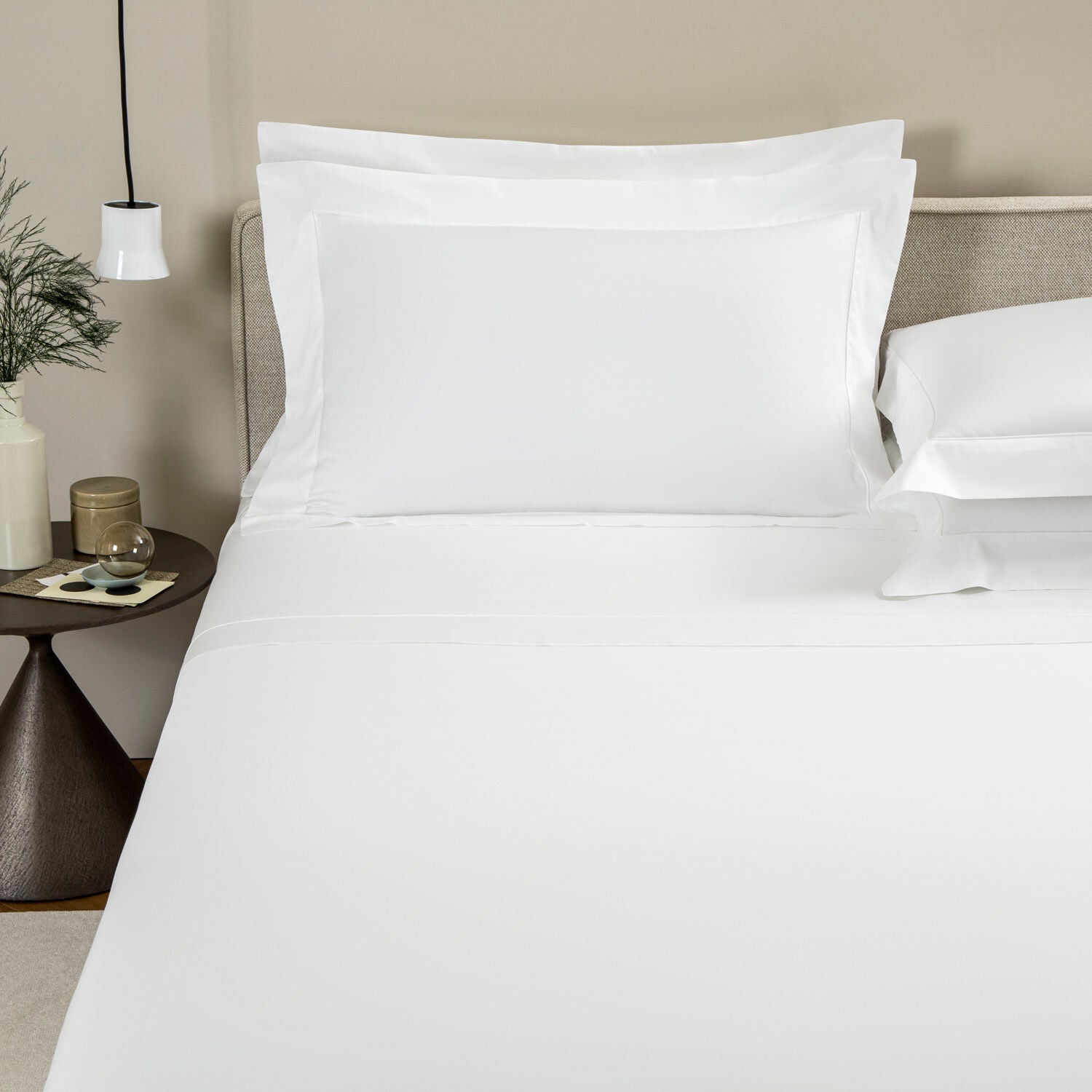 Neatly made bed with white bedding in a bedroom setting.