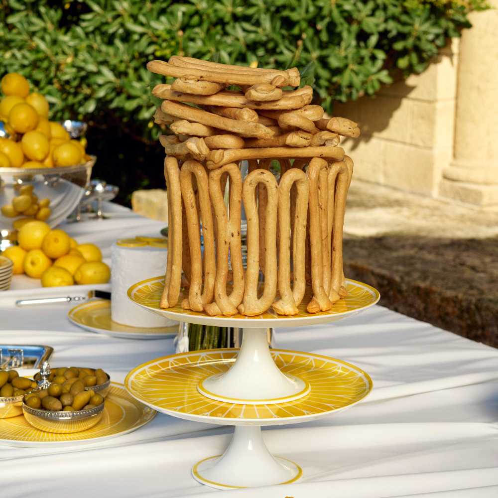 Yellow cake stand with sunburst pattern on a white background