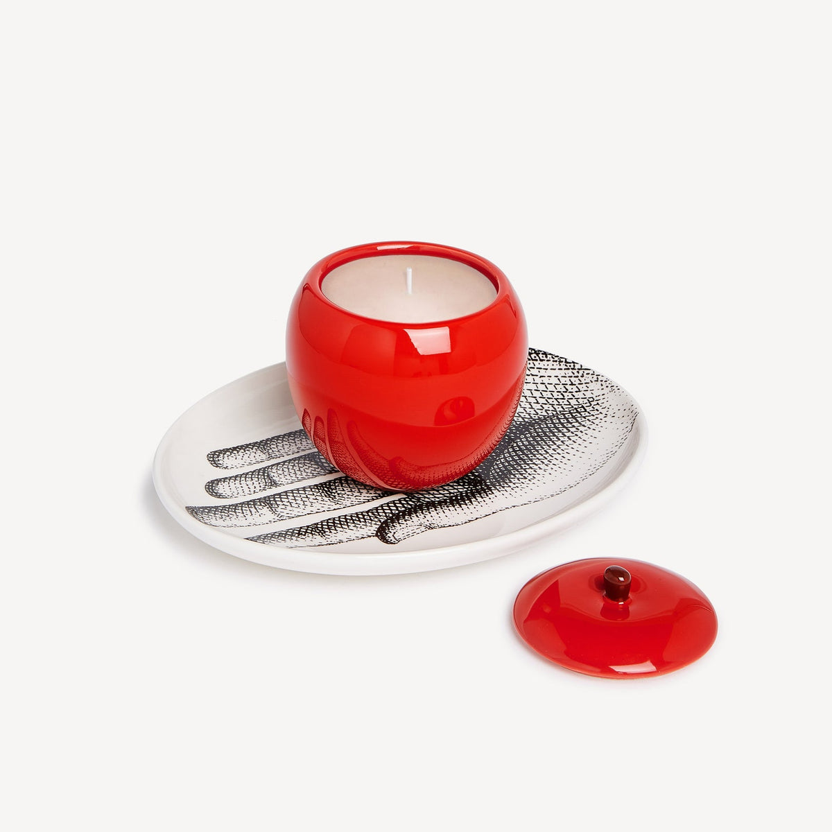 Red ceramic apple-shaped candle holder with a white candle on a textured metal stand against a white background.