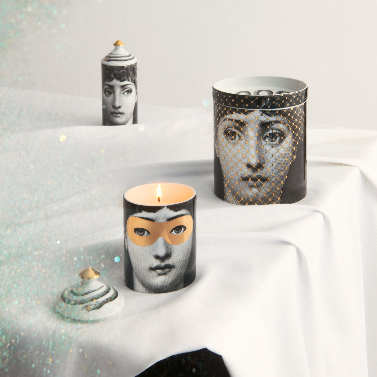 Candles with artistic face designs on a white surface