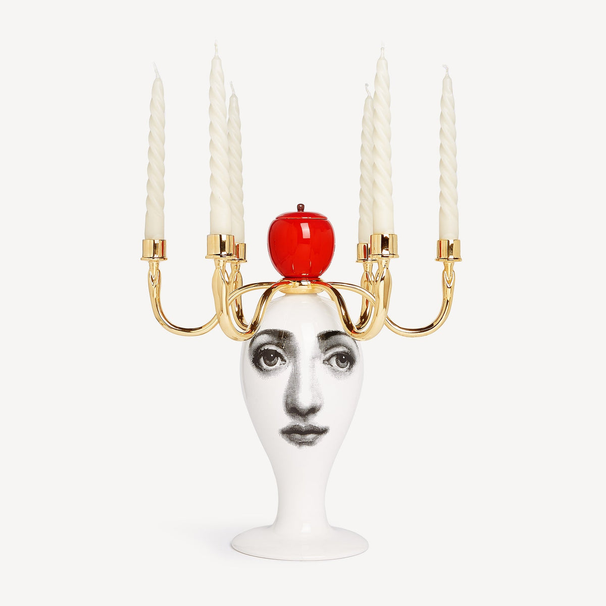 Candle holder with face design and red apple on a white background