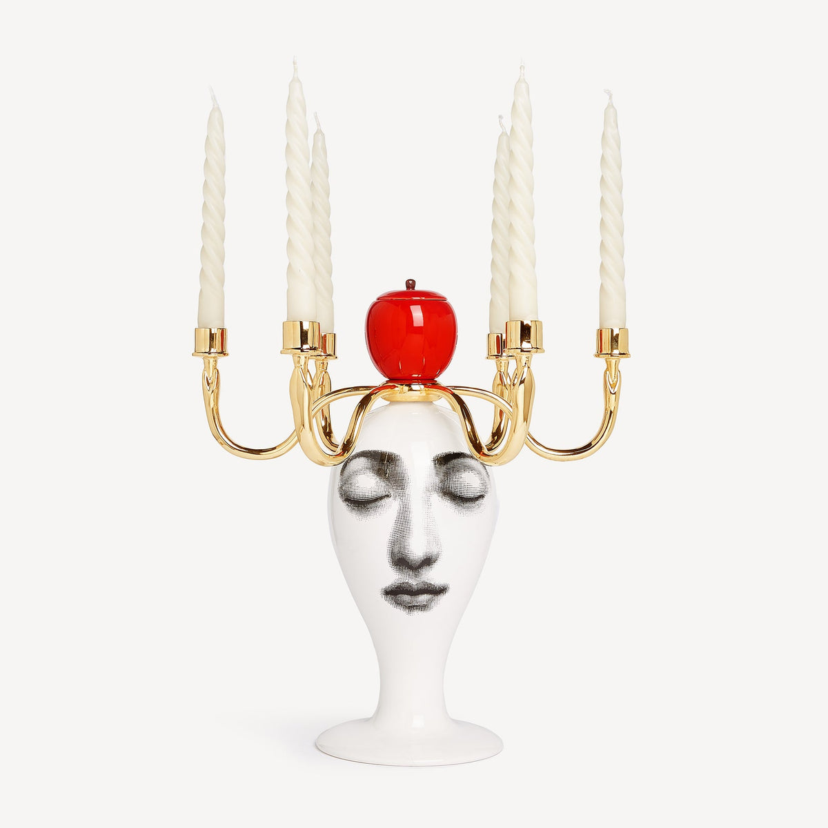 Candle holder with face-shaped base and red apple on a white background