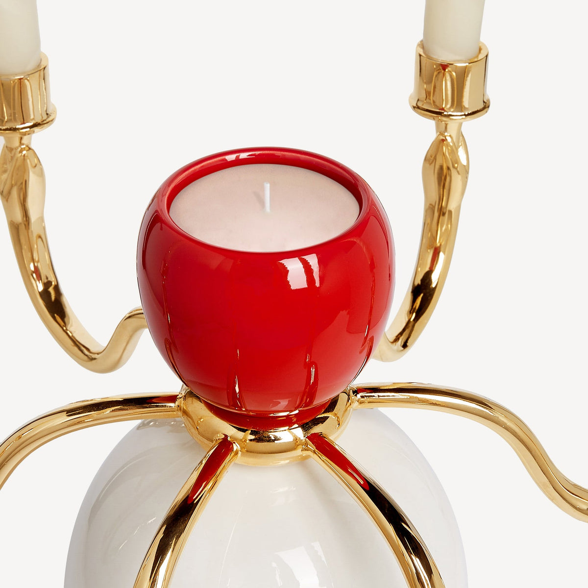 Decorative candle holder with red center, gold accents, and white candles on a white background