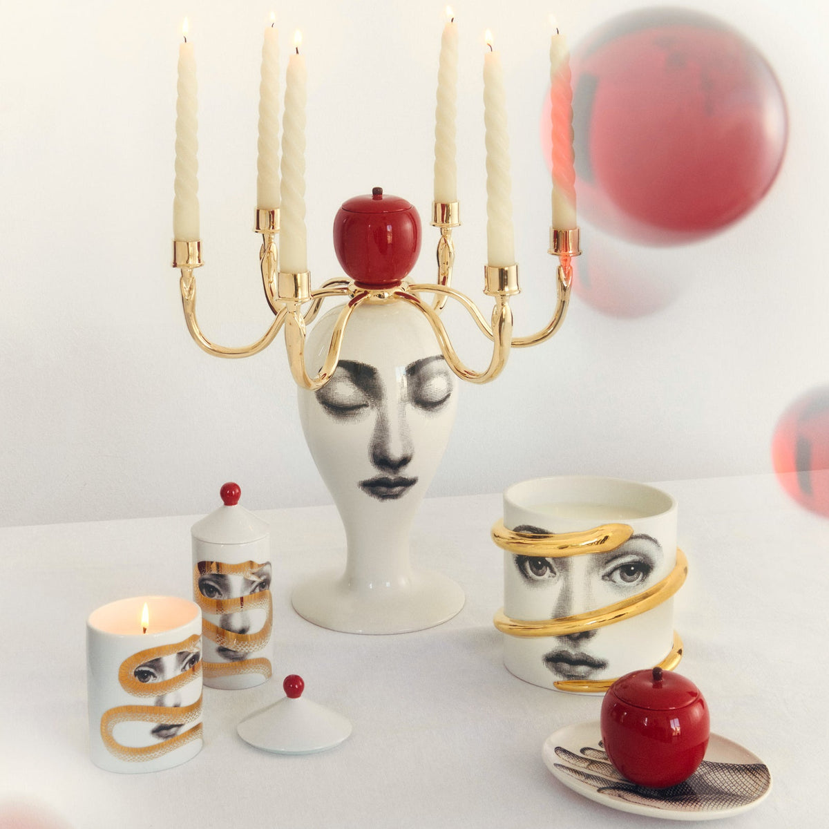 Decorative items including a candle holder, cups, and vases with artistic designs on a white background.