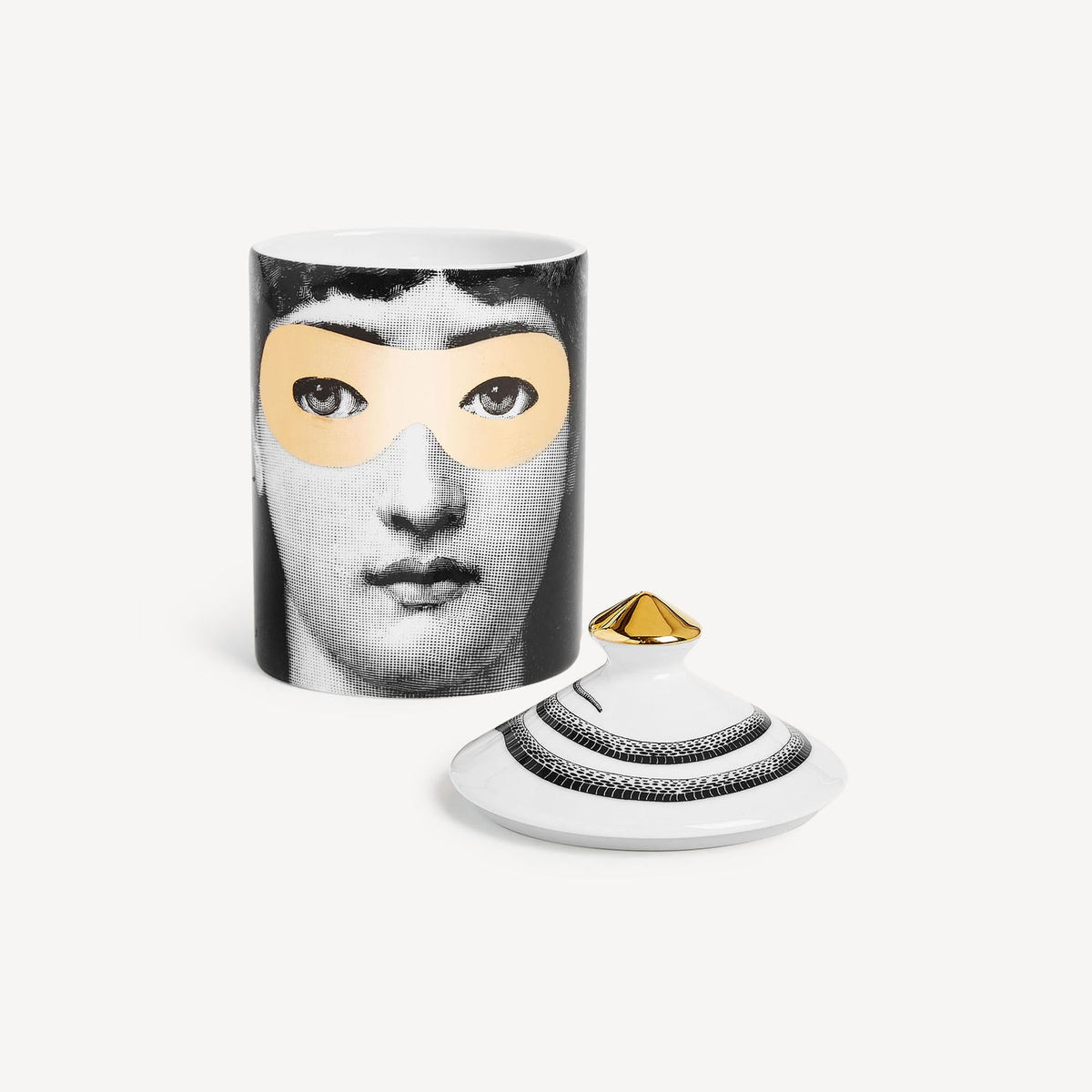 Candle with face design and gold accents on a white background