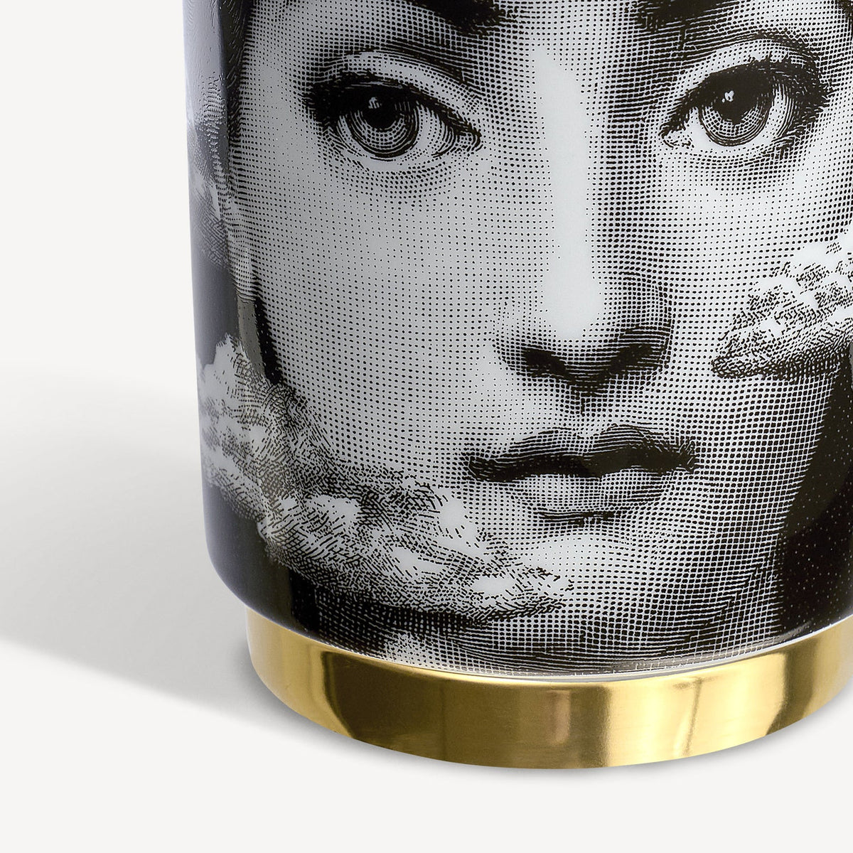 Cylindrical container with a black and white face design and gold base on a white background
