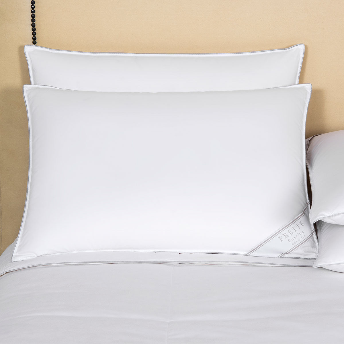 White pillows on a bed with a beige wall in the background
