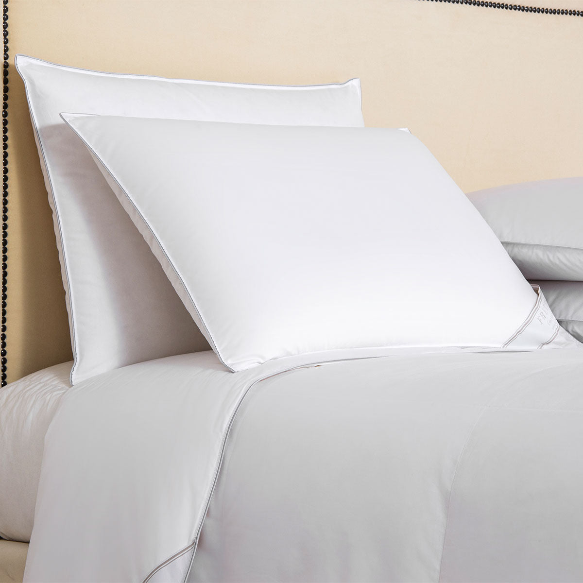 White pillows on a bed with a beige wall in the background
