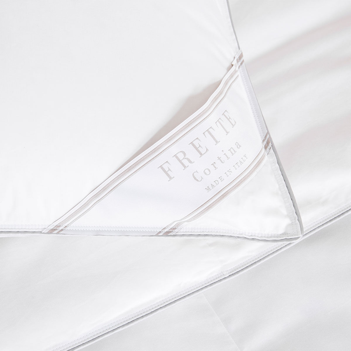 Close-up of a white satin pillowcase with 'Frette' branding.