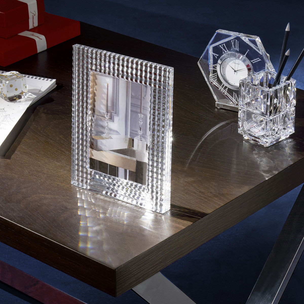 Crystal photo frame, clock, and pen holder on a reflective surface with a dark background