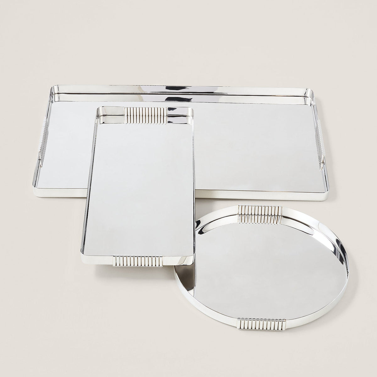 Set of three silver compact mirrors on a beige background