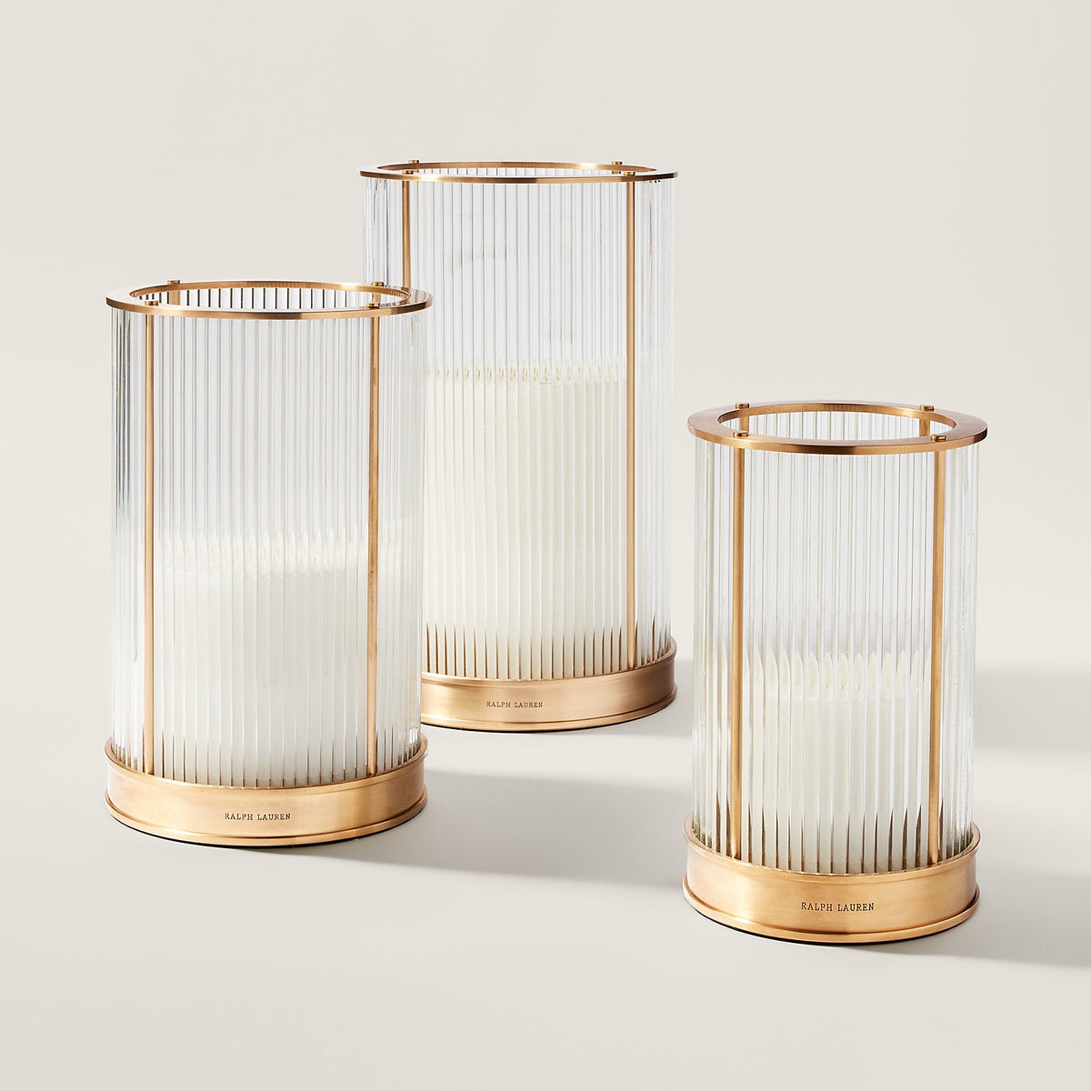 Three gold candle holders with white candles on a light beige background