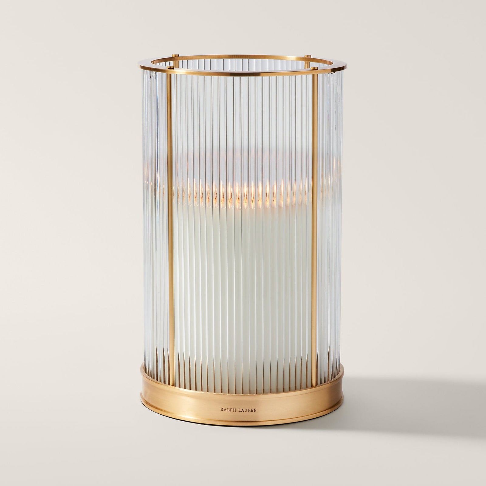 Decorative candle holder with brass base and glass cage on a white background