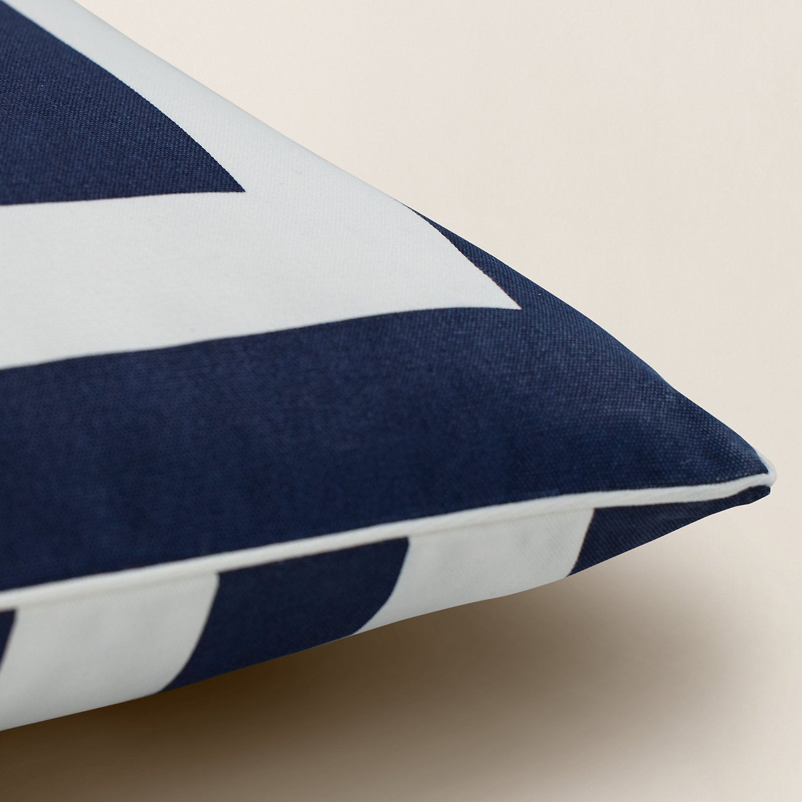 Navy blue pillow with a white center featuring a logo on a beige background