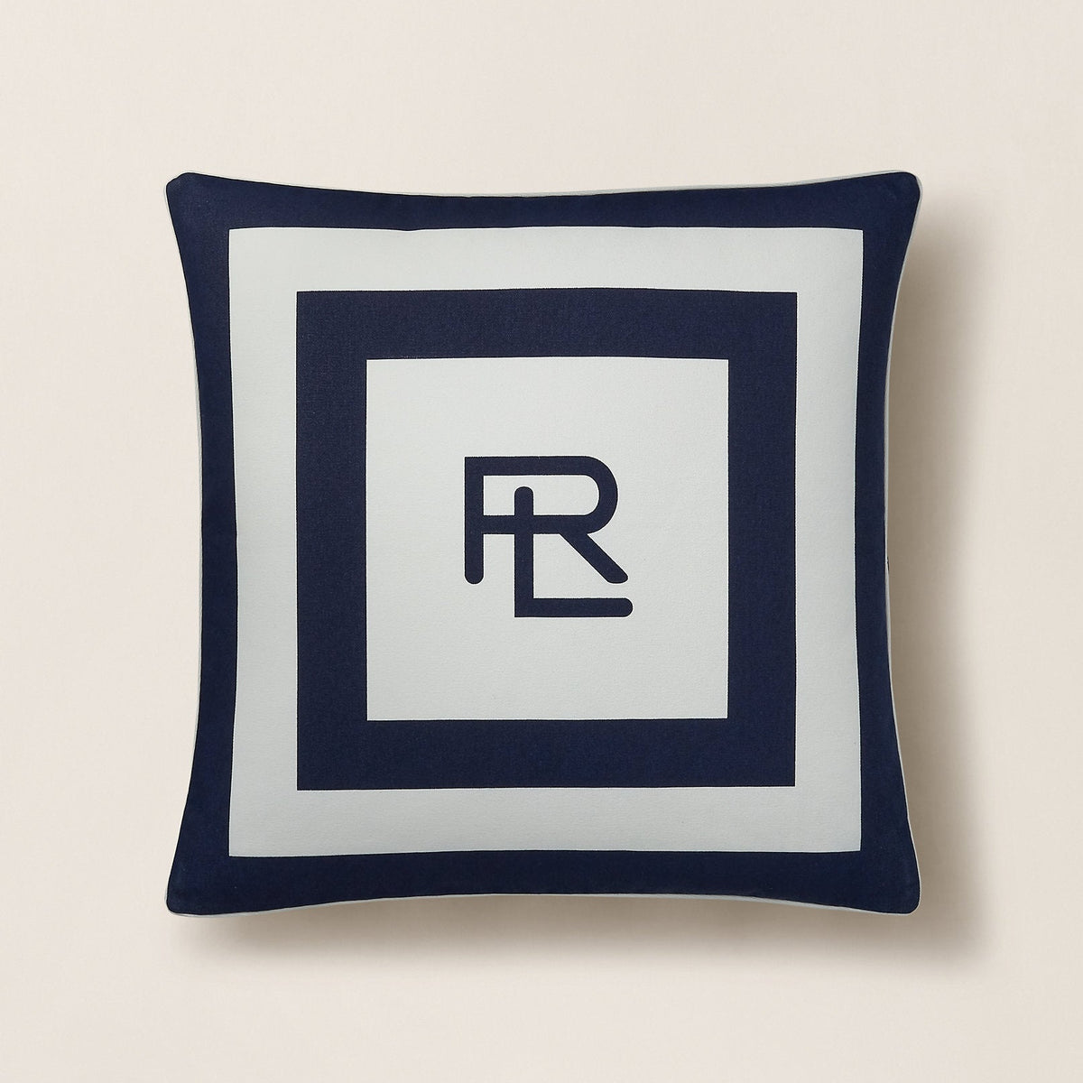 Navy blue pillow with a white center featuring a logo on a beige background