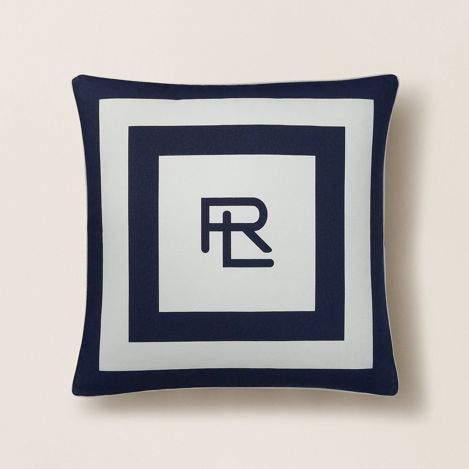 Navy blue pillow with a white center featuring a logo on a beige background
