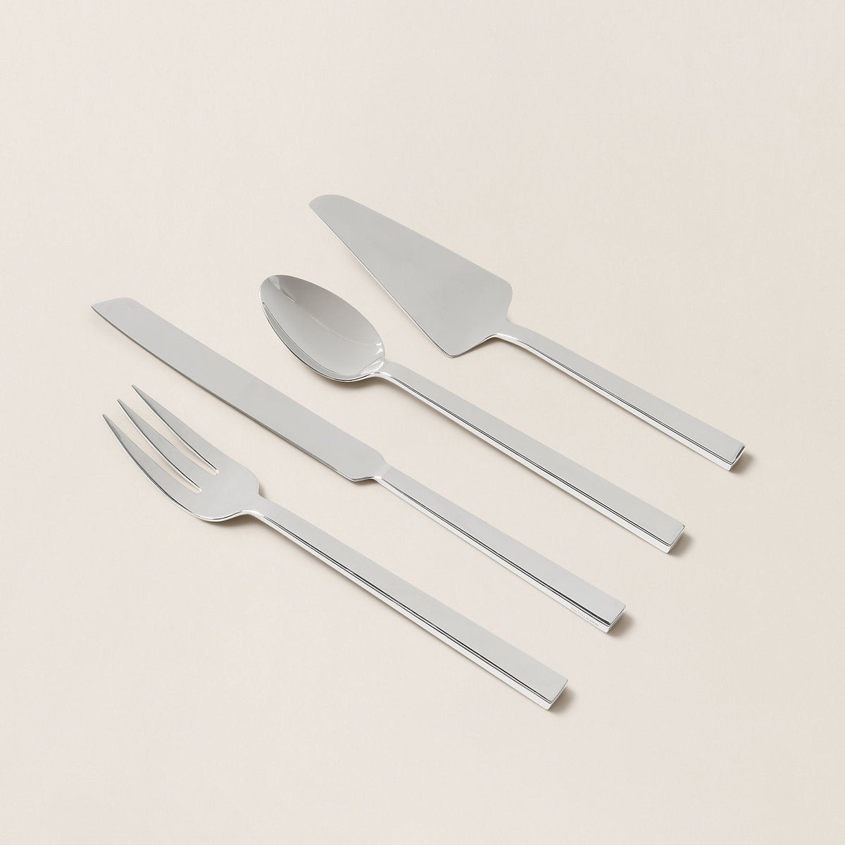 Set of silver cutlery including a knife, fork, and spoon on a beige background