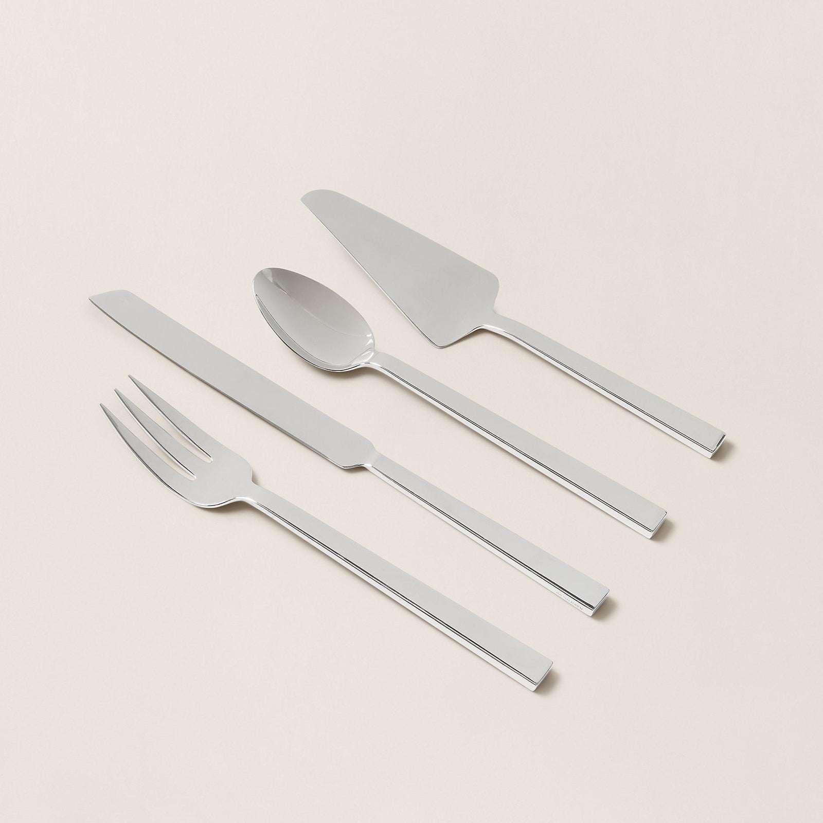 Set of silver cutlery including a knife, fork, and spoon on a beige background