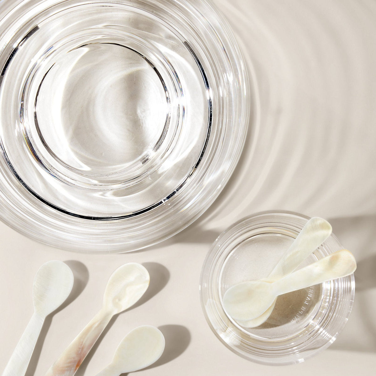 Clear glass containers with white spoons on a light beige background