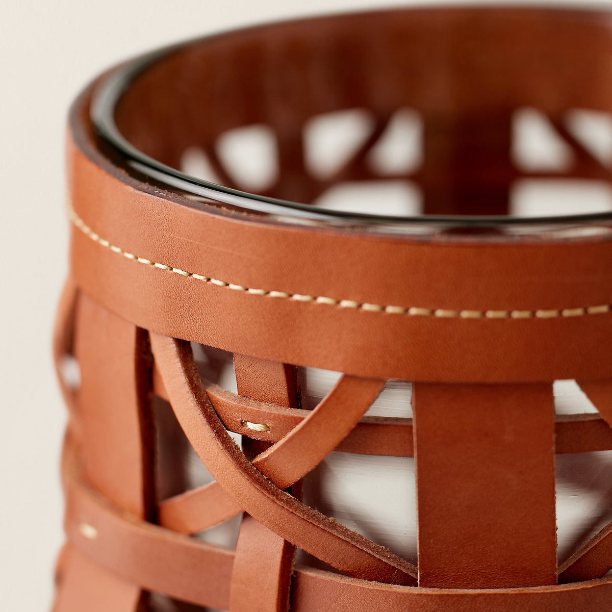 Close-up of a brown woven leather basket on a light background