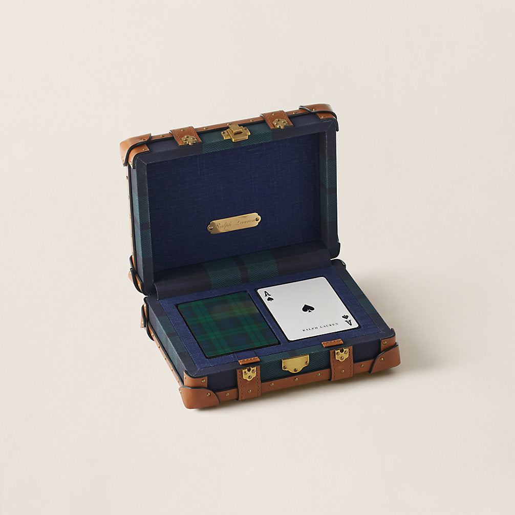 Open suitcase with playing cards on a beige background