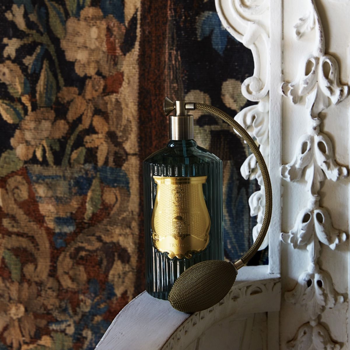 Decorative lamp with gold and black design against a textured wall.