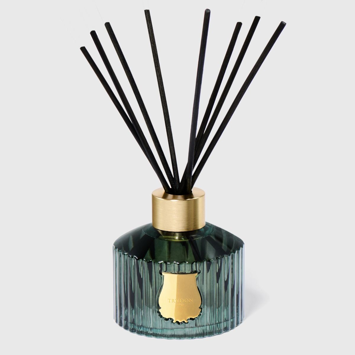 Reed diffuser with black reeds and a green bottle on a light gray background