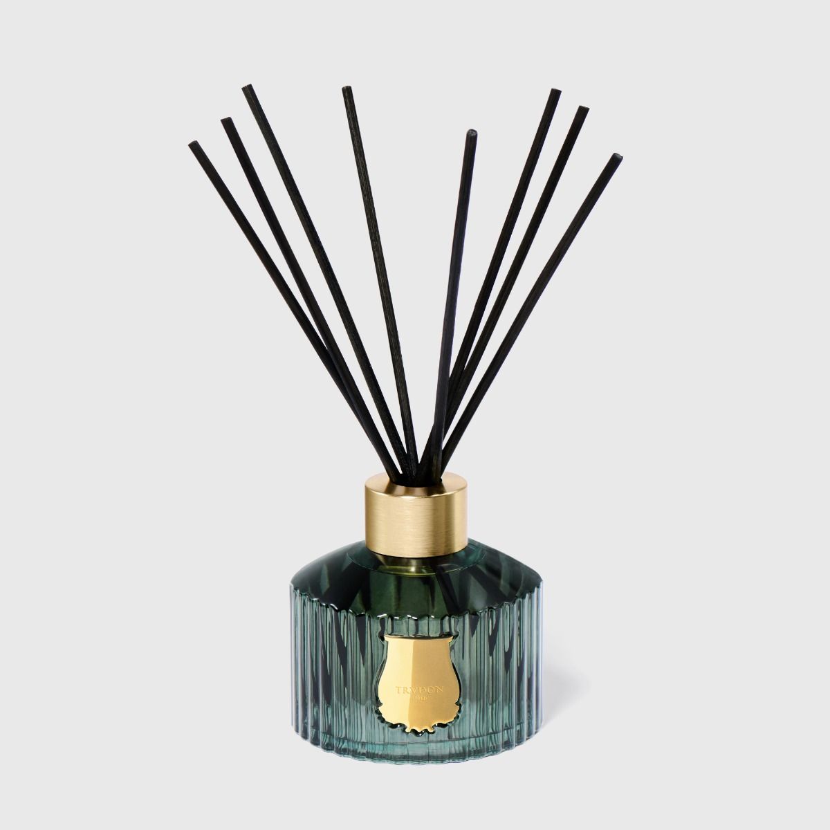 Reed diffuser with black reeds and a green bottle on a light gray background